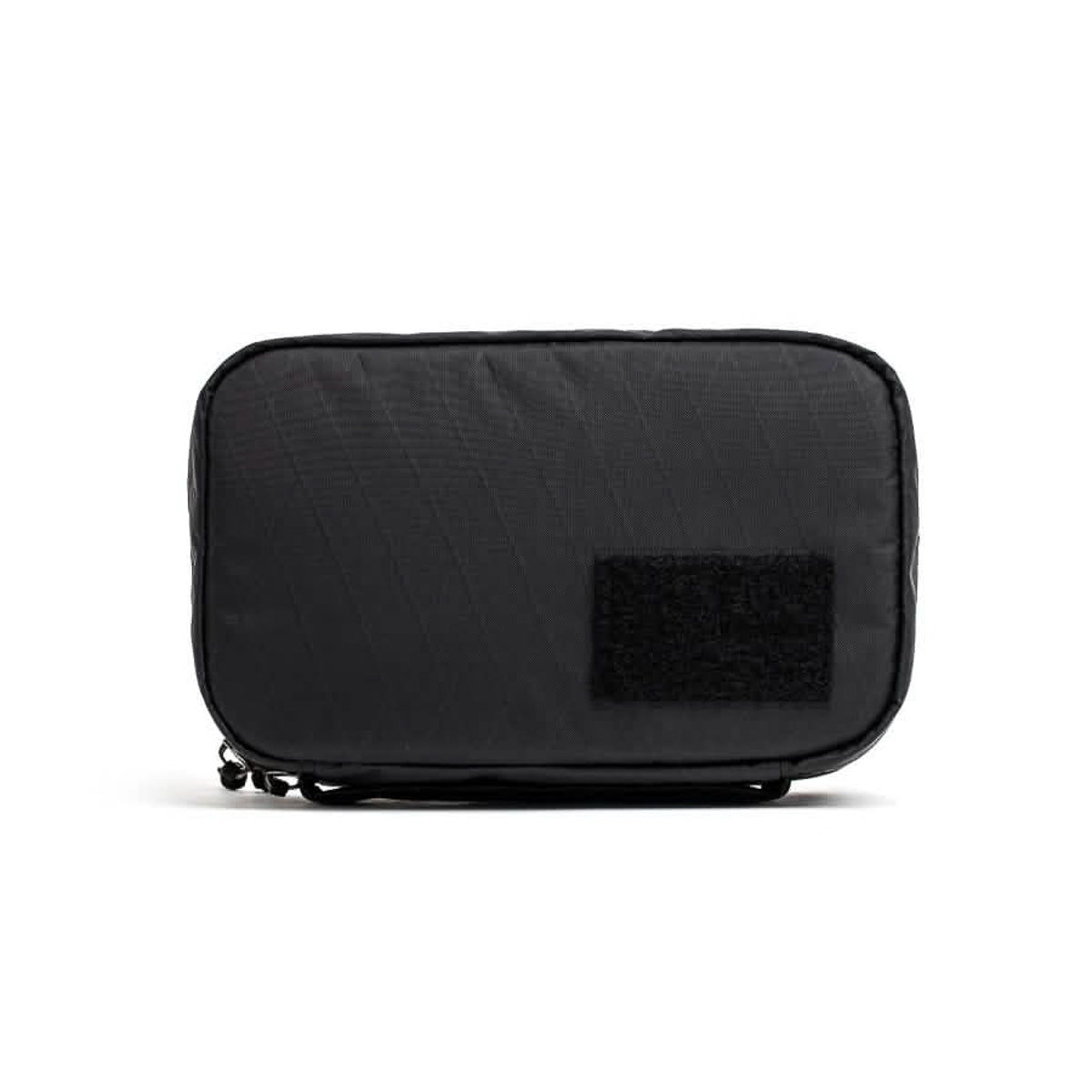 The GR1 Field Pocket USA - X-PAC is a rectangular black pouch featuring durable X-PAC material and a small velcro patch on the front, perfect as a travel accessory and shown on a white background.