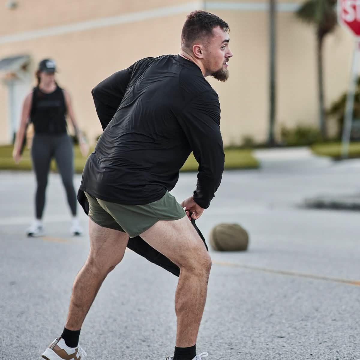 Man wearing GORUCK ToughMesh LS Black shirt outdoors, rucking with sandbag on street