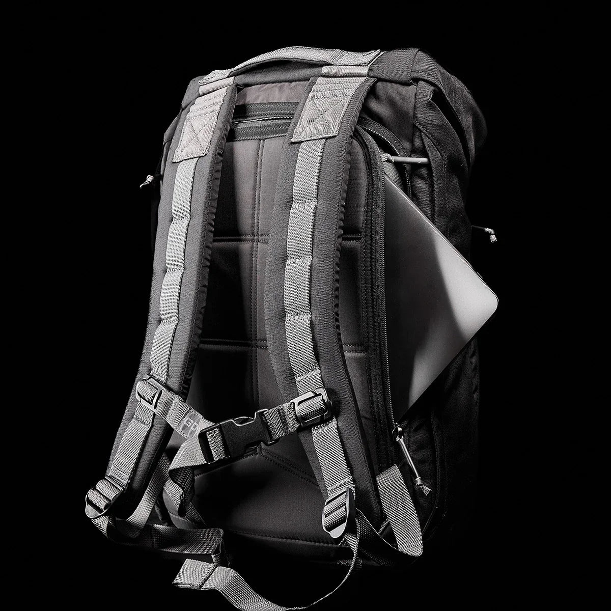 Black rugged GORUCK backpack with padded straps and a laptop partially inserted in side compartment