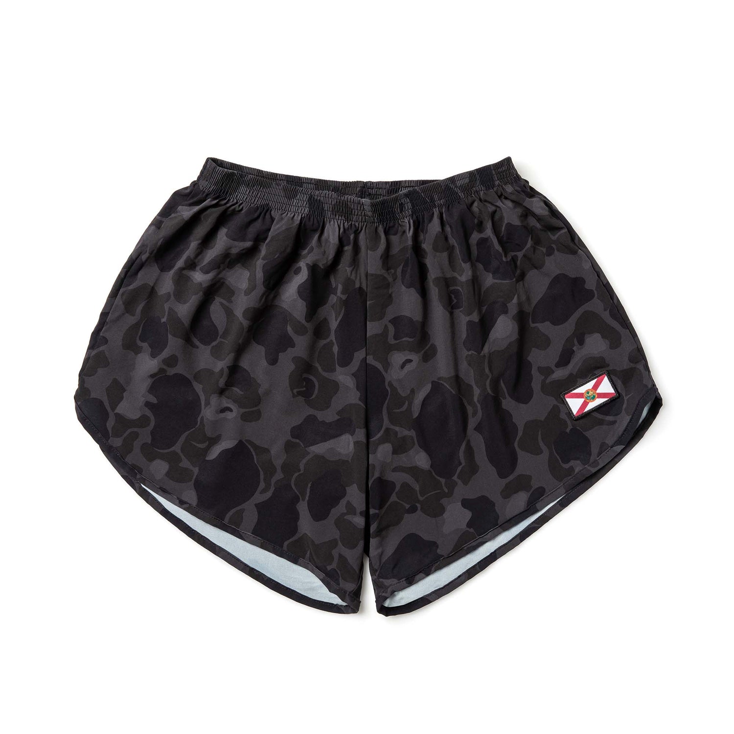 The Men’s Ranger Panties - ToughStretch are black camo PT shorts crafted from durable ToughStretch fabric, with a small rectangular patch on the lower right leg.