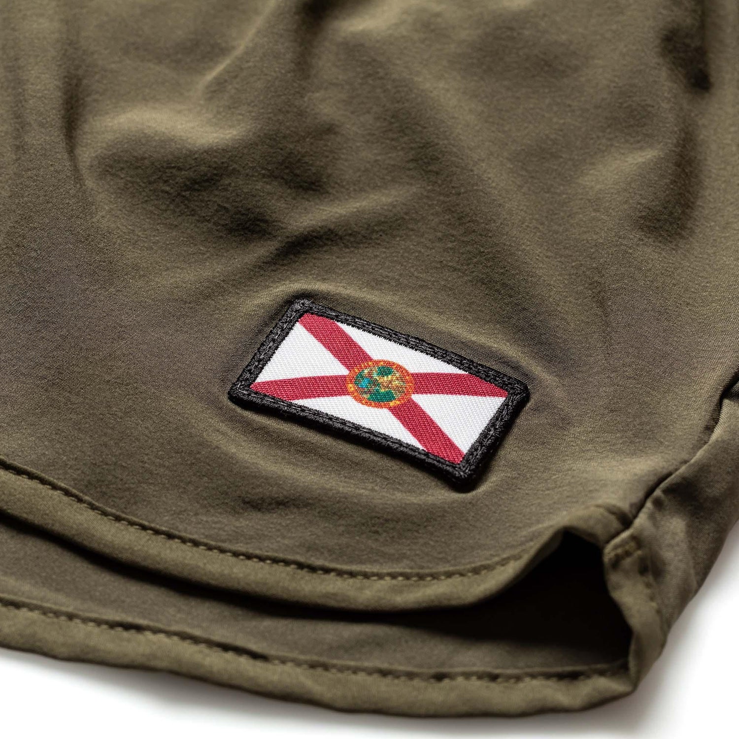 Close-up of olive green fabric with a stitched Florida state flag patch, showcasing durable material and fine stitching