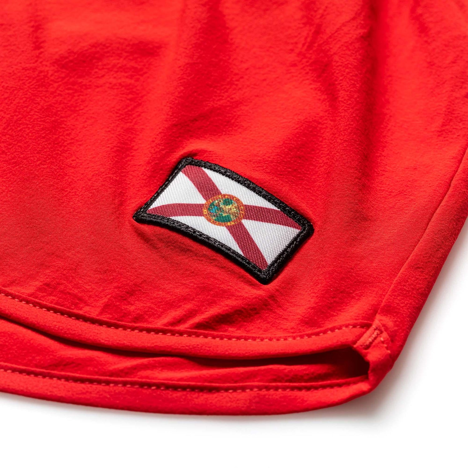 Close-up of red rugged fabric pants with embroidered Florida state flag patch, durable stitching