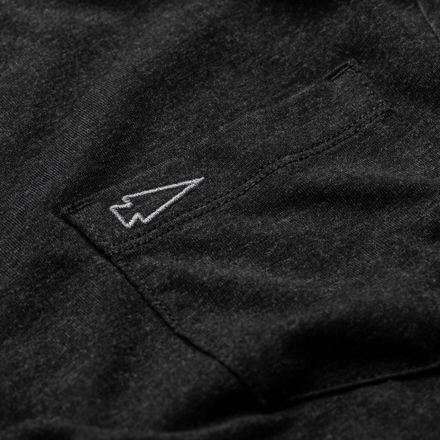 Close-up of the Men's Short Sleeve Pocket Tee - Tri-Blend in premium black, crafted from ultra-soft Tri-BlendX fabric with a small white-outlined paper airplane stitched above the pocket.