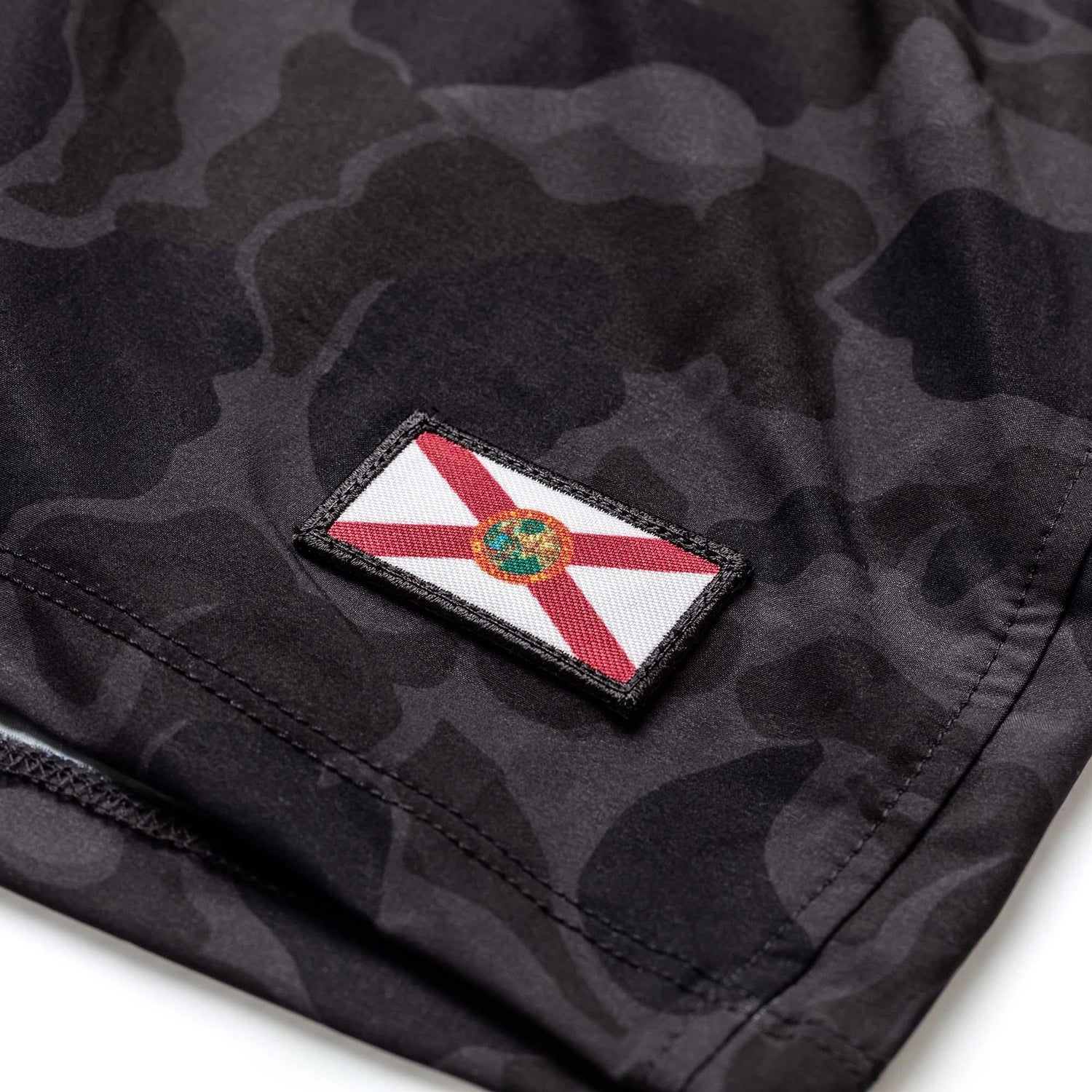 Close-up of black frogskin camo men's training shorts with Florida flag patch detail