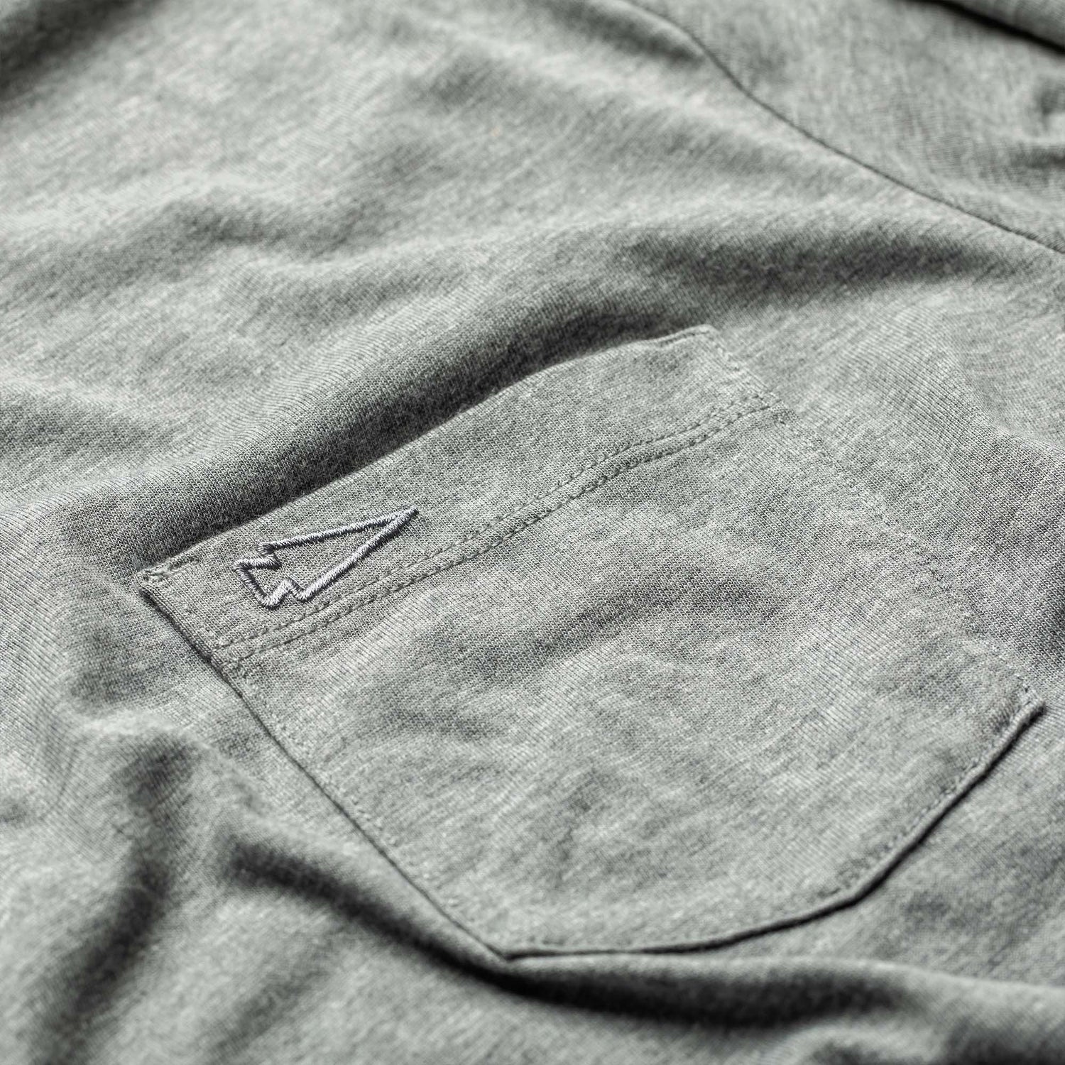 Close-up of the Men's Polo with Pocket - Tri-Blend in gray, featuring an embroidered arrow logo above the pocket.