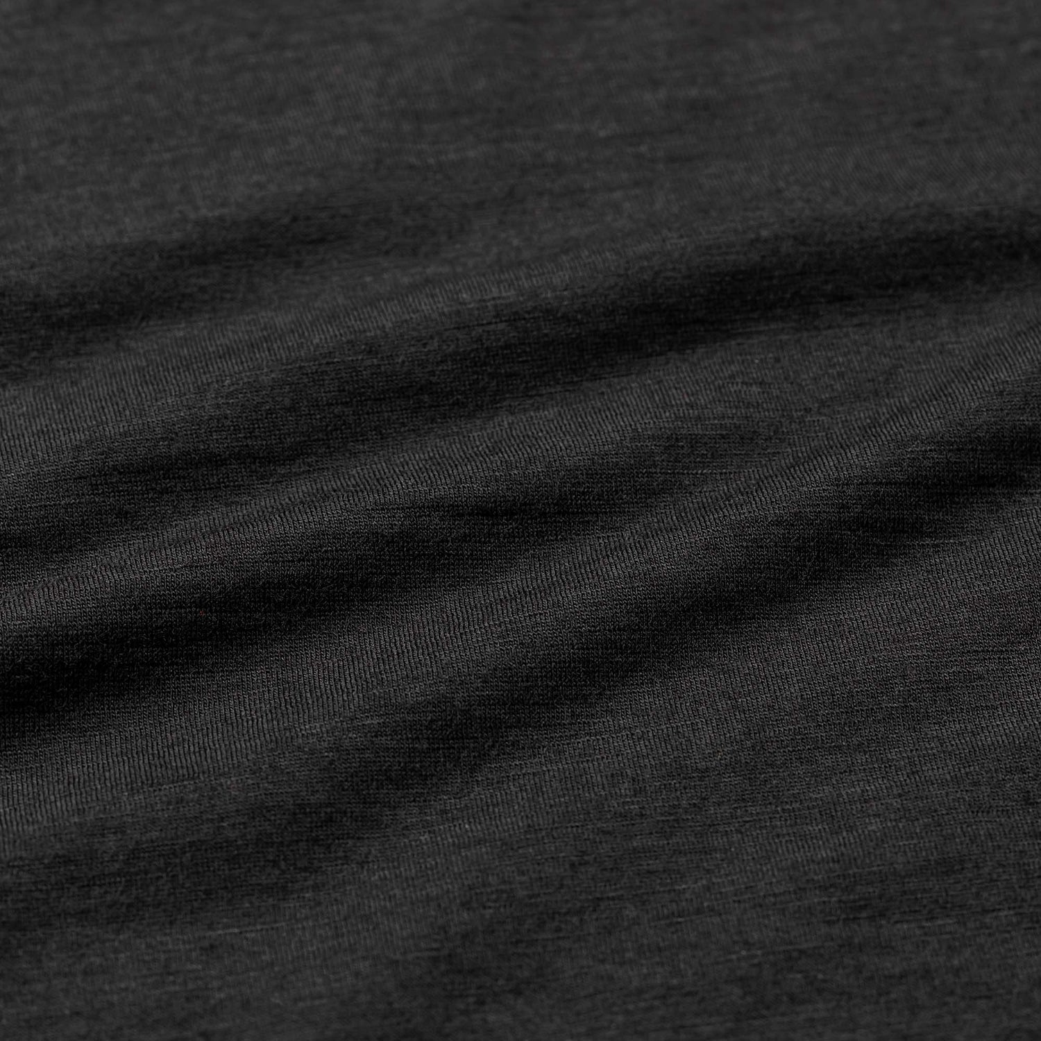 Close-up of the Men’s Commando Tee - Merino Wool in black, highlighting the soft texture and subtle horizontal folds of its premium merino wool fabric.