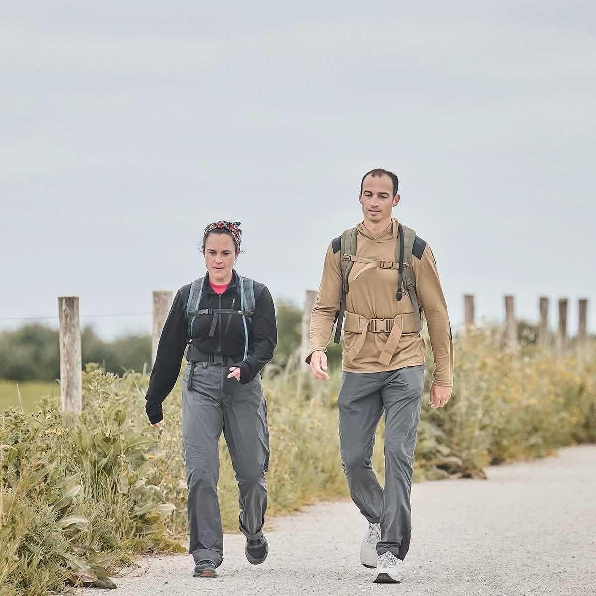 Two hikers walking on a trail wearing GORUCK gear with backpacks and outdoor clothing in a grassy area