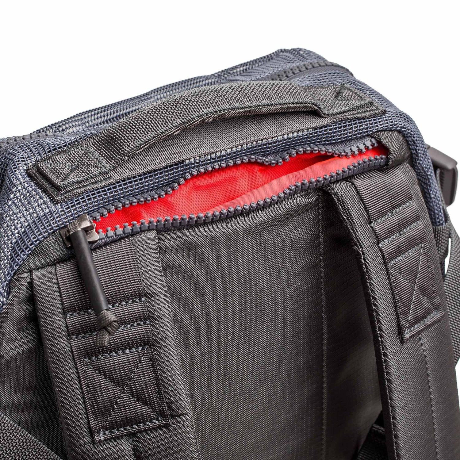 Close-up of the Mesh Ruck, a black quick-drying backpack featuring padded straps and a partially open zipper that reveals its red interior.