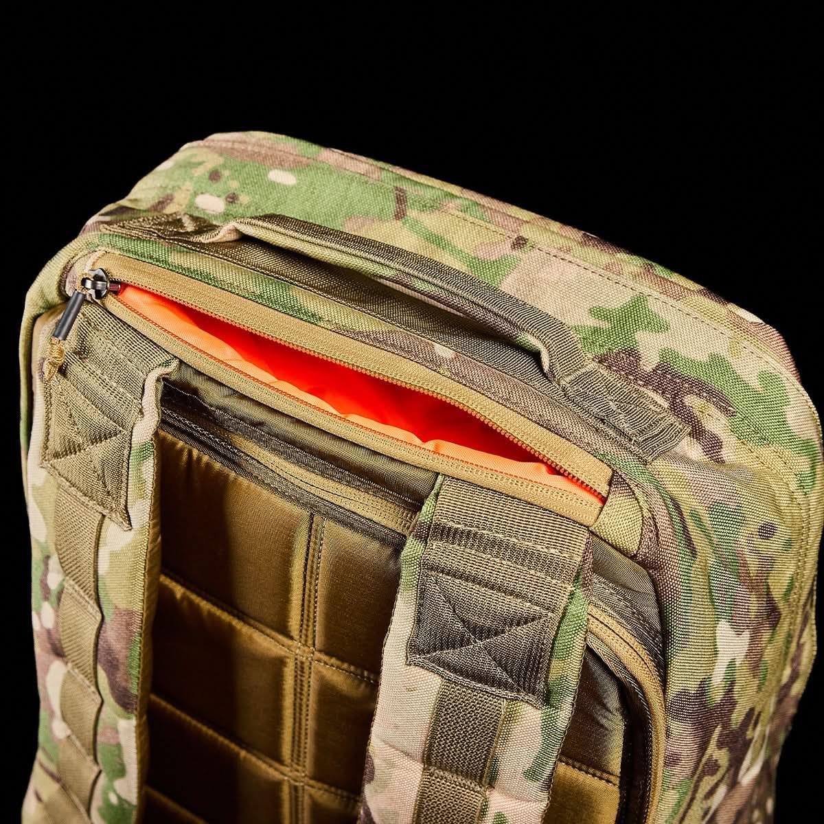 Close-up of rugged multicam camo GORUCK backpack top with padded straps and bright orange zipper lining