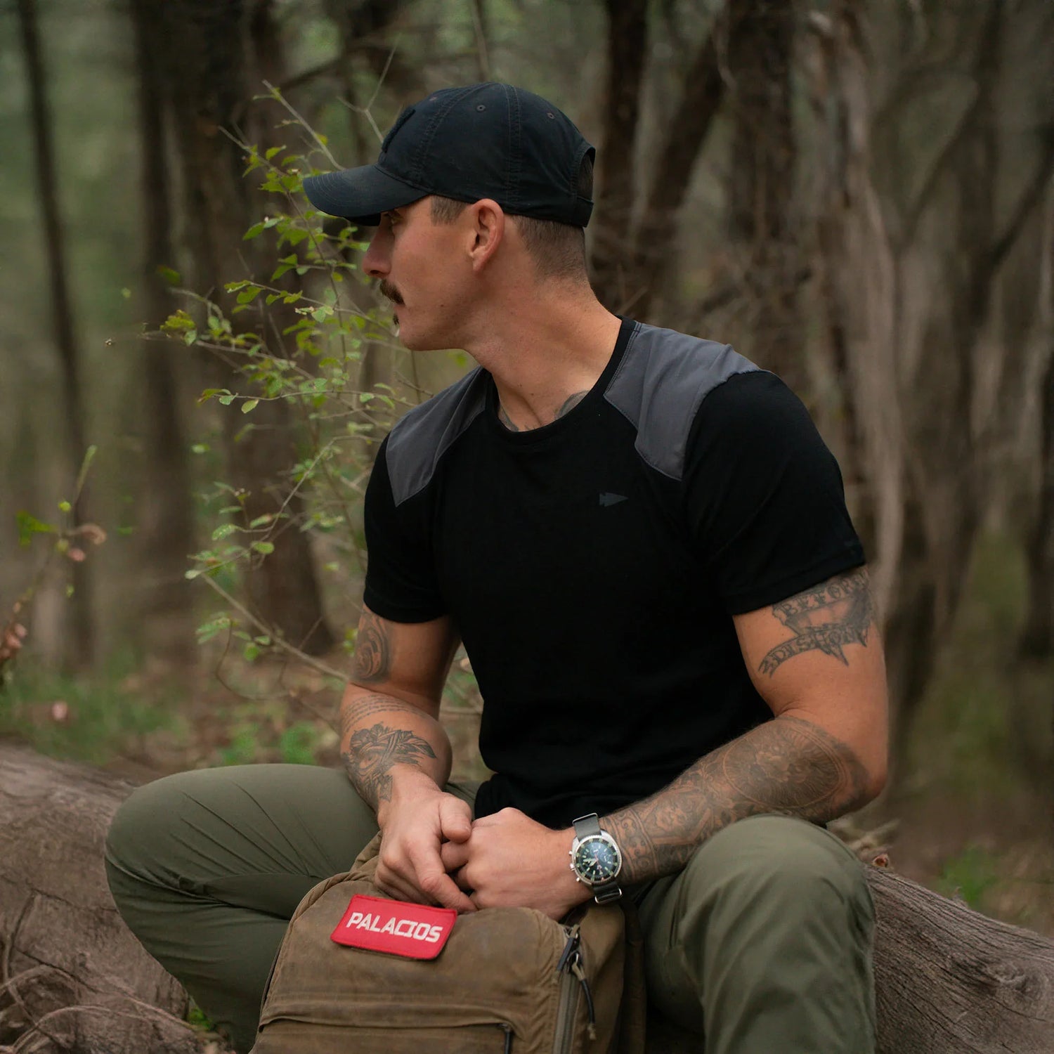 Man in GORUCK gear with tactical backpack sitting in forest, outdoor rucking setting