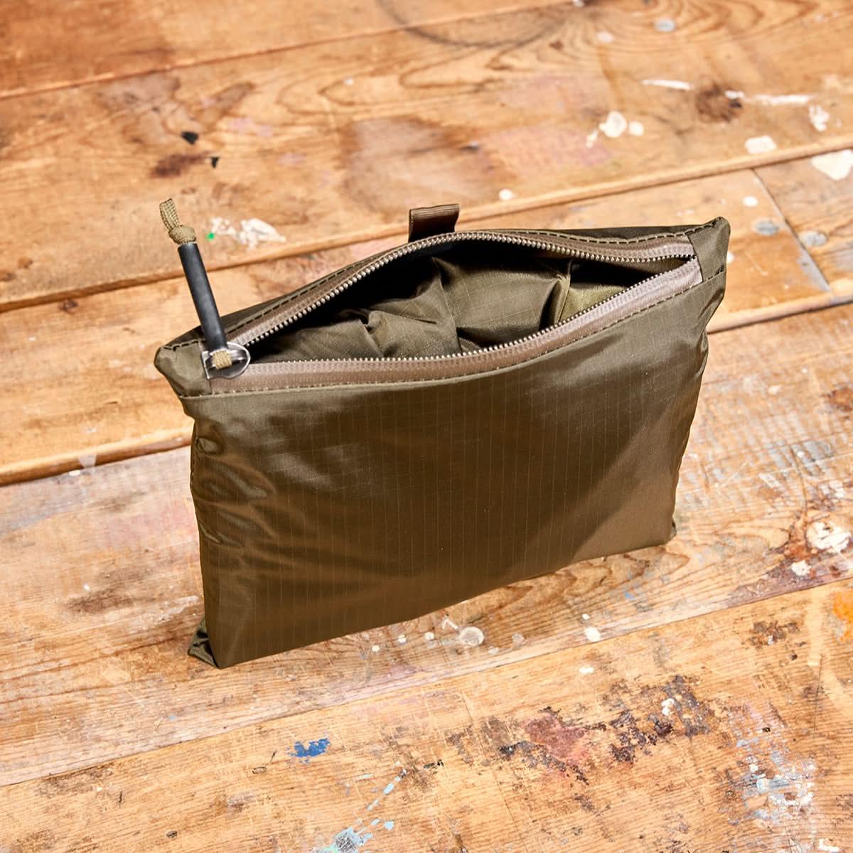 GORUCK bullet proof packable bag in ranger green with zipper, set on worn wooden surface