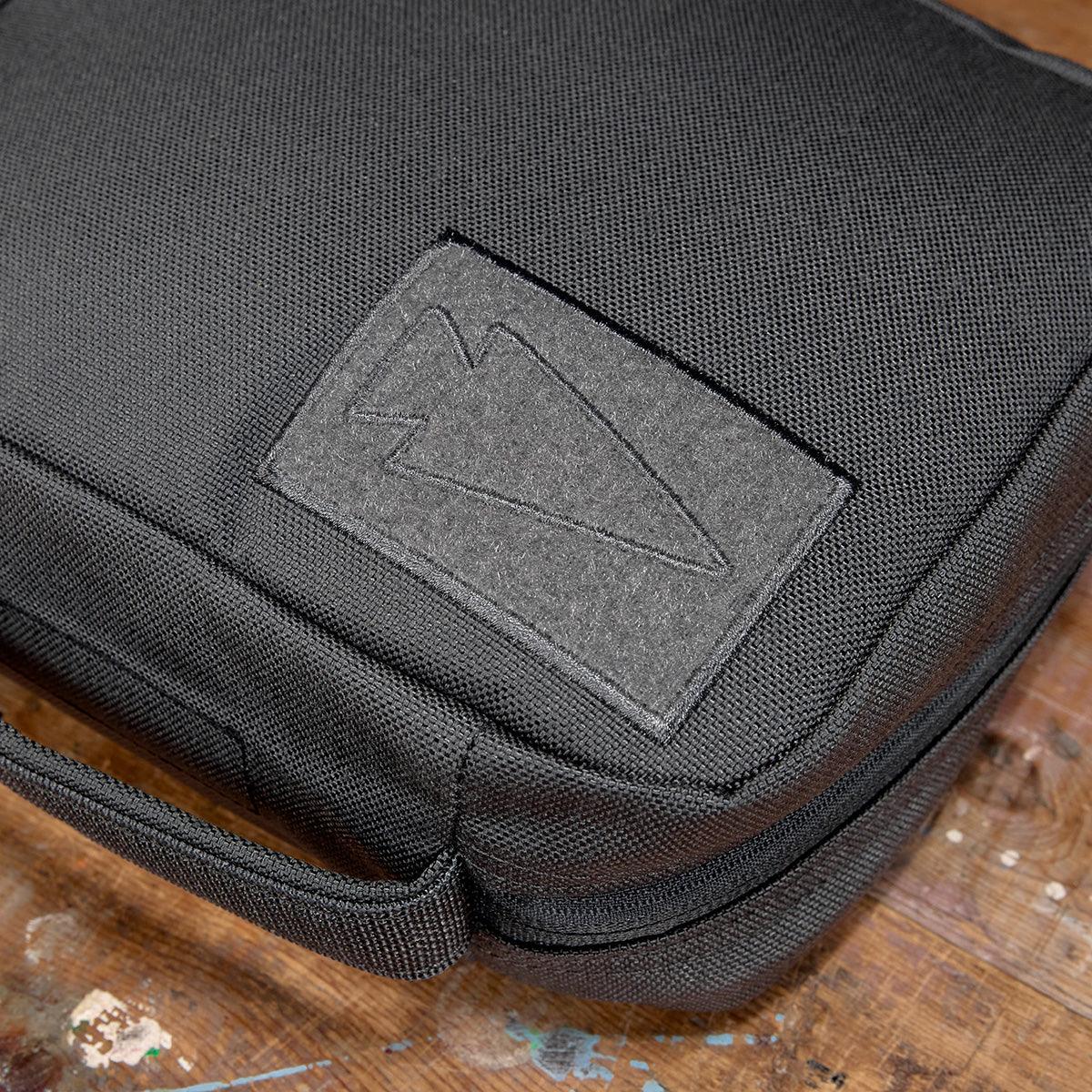 Close-up of black padded field pocket gear pouch with GORUCK logo on wooden surface