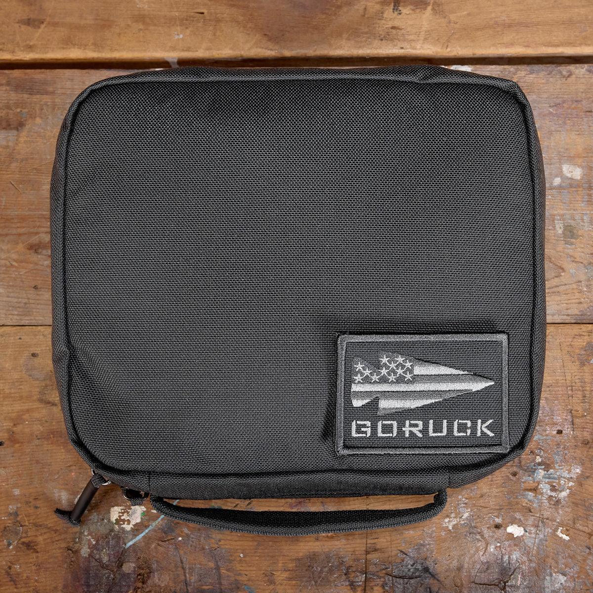 Black GORUCK padded field pocket pouch with logo patch on wooden surface
