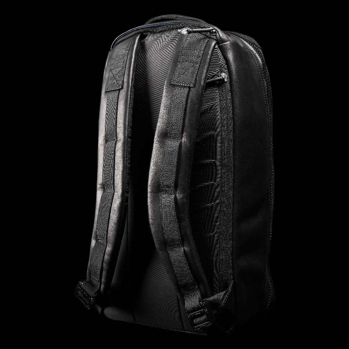 Black backpack shown from the back, highlighting padded shoulder straps and textured back panel.