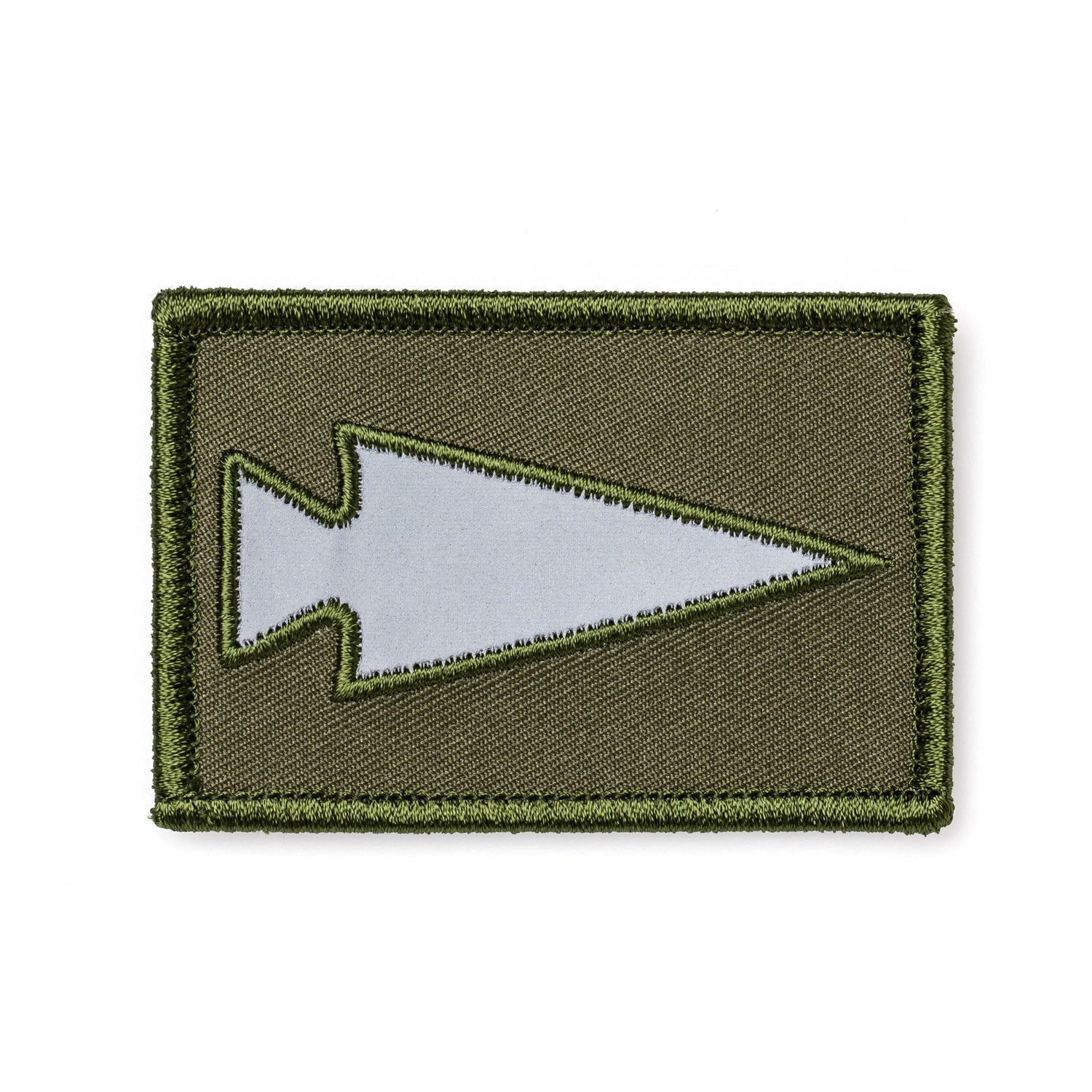 The Patch - Reflective Spearhead by GORUCK displays a gray spearhead emblem on a dark green backdrop, outlined in olive green. It includes a VELCRO® backing for convenient attachment.