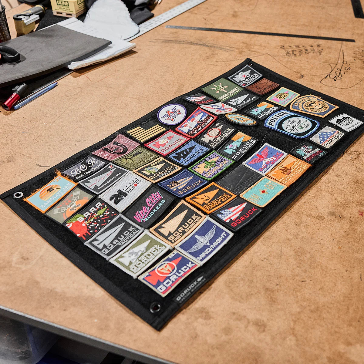 GORUCK patch board with diverse rucking, tactical, and event patches on workshop table