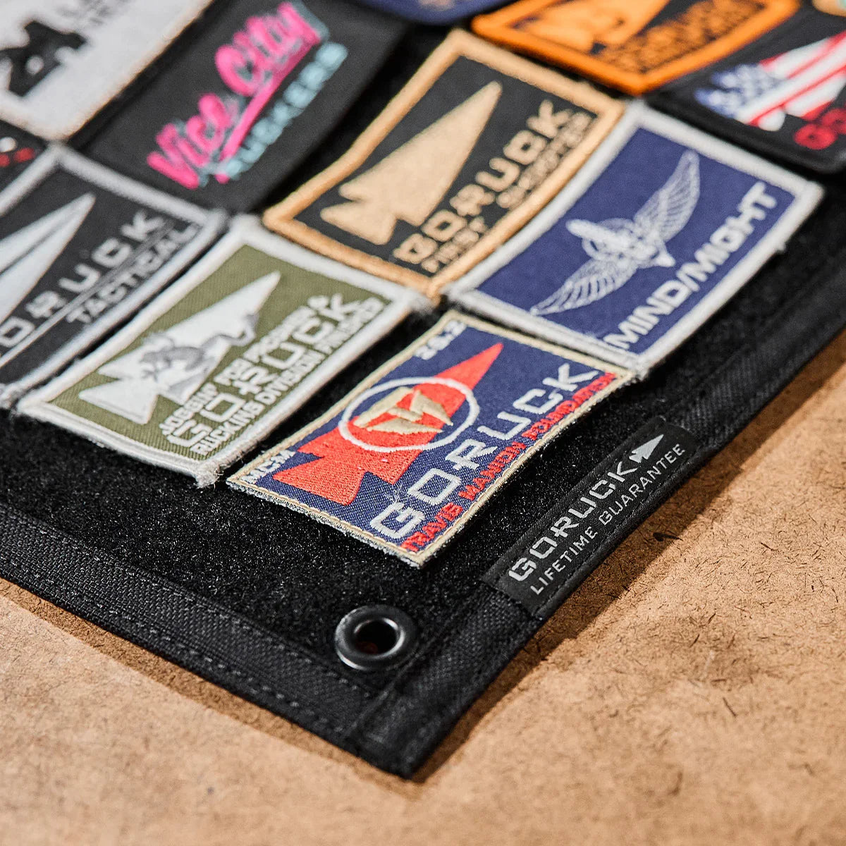 Close-up of a GORUCK patch board featuring multiple rugged embroidered rucking patches on black fabric