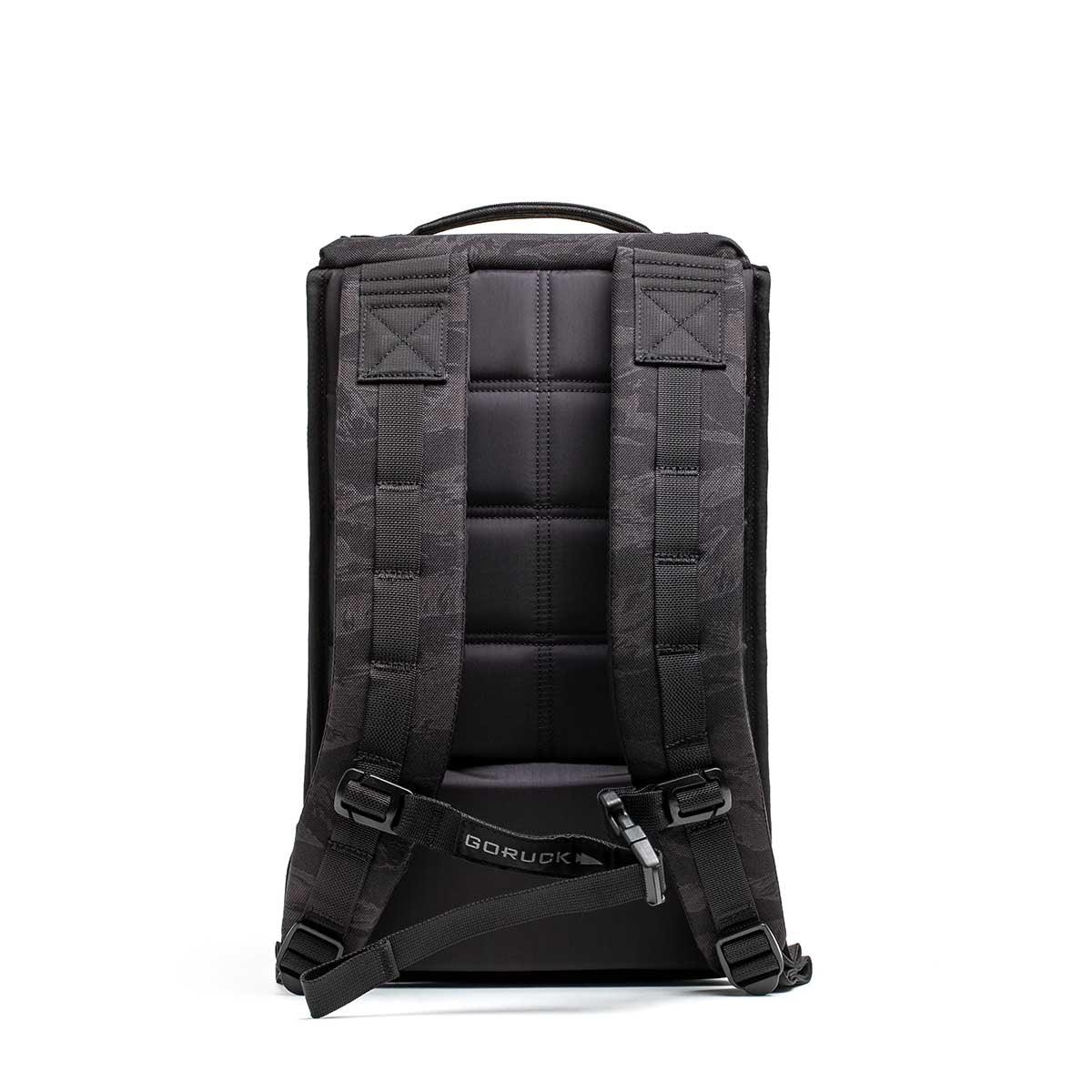 Back view of a black GORUCK tactical rucksack with padded straps and adjustable chest buckle on white background