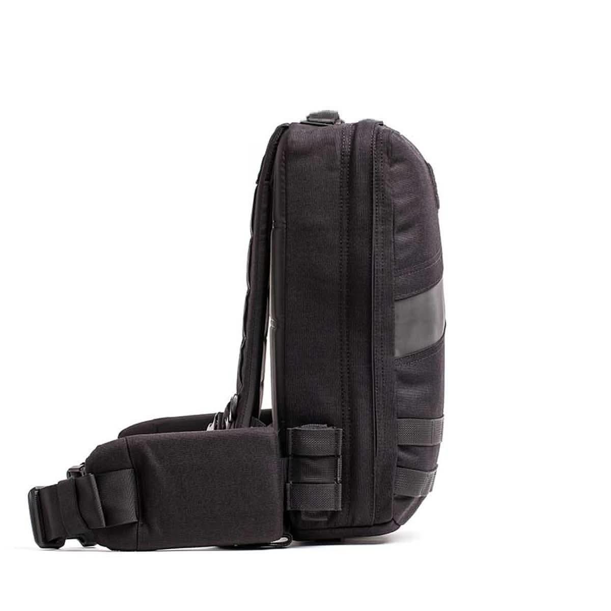 Side view of black GORUCK 15L pack with padded hip belt and MOLLE webbing against white background