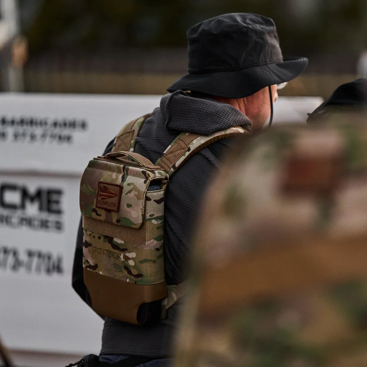 Person wearing GORUCK multicam ruck plate carrier with black bucket hat and gray hoodie in outdoor setting