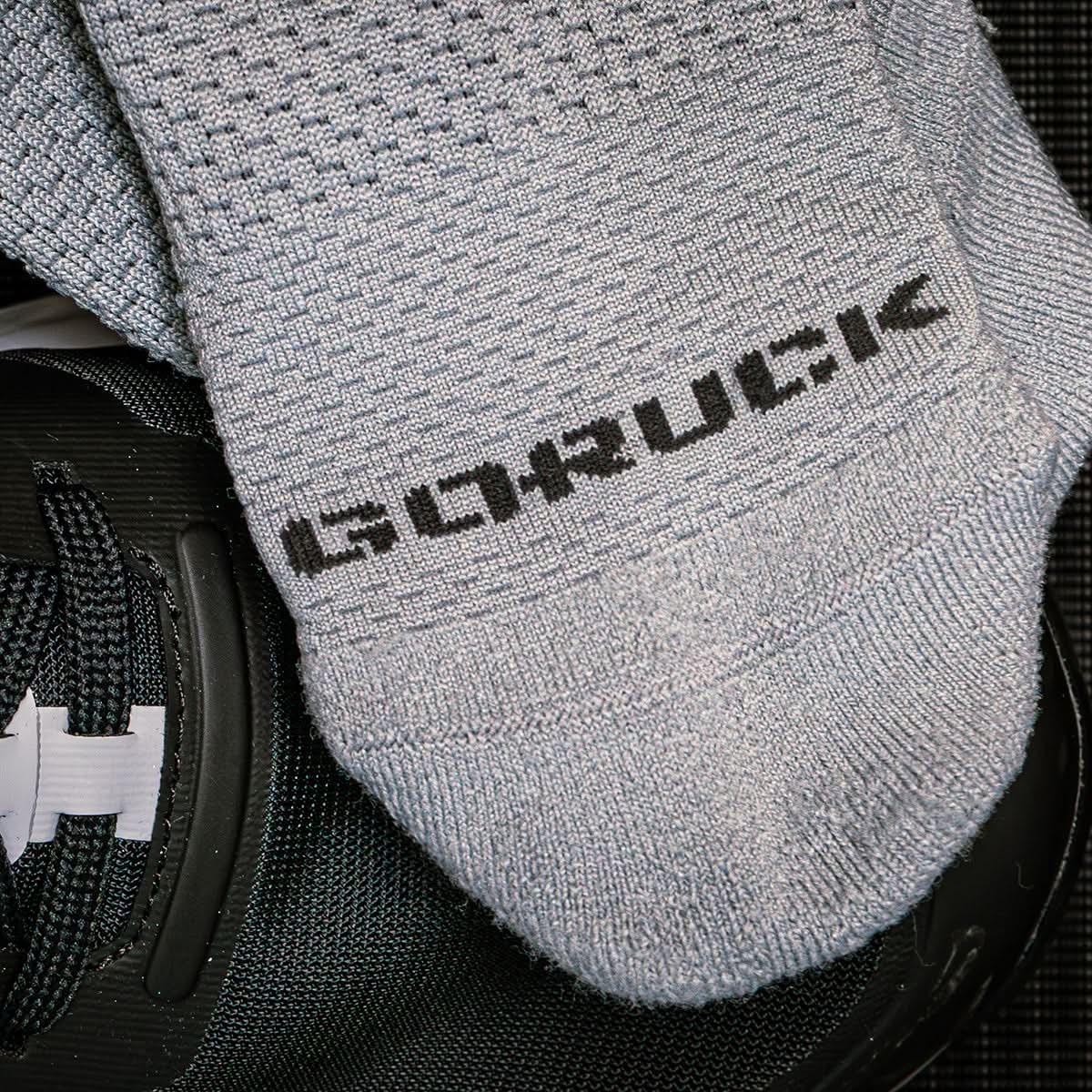 Close-up of gray GORUCK branded performance socks placed on black athletic shoes