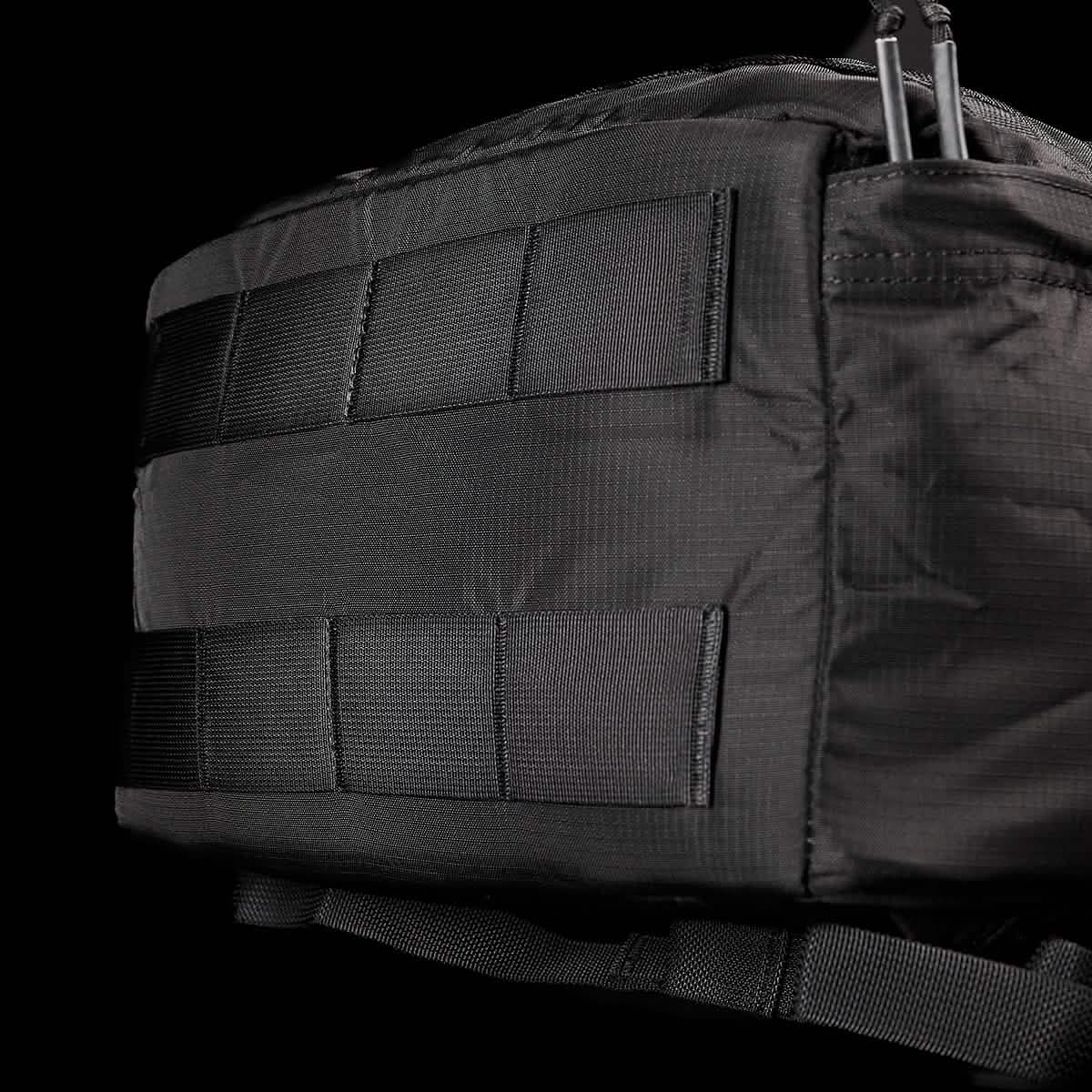 A close-up of the GORUCK GR3 - Ripstop ROBIC® tactical carry-on rucksack highlights its rugged texture, crafted from durable Robic nylon, and numerous horizontal webbing straps along the side. The dark background accentuates the bag's distinctive GR3 features.