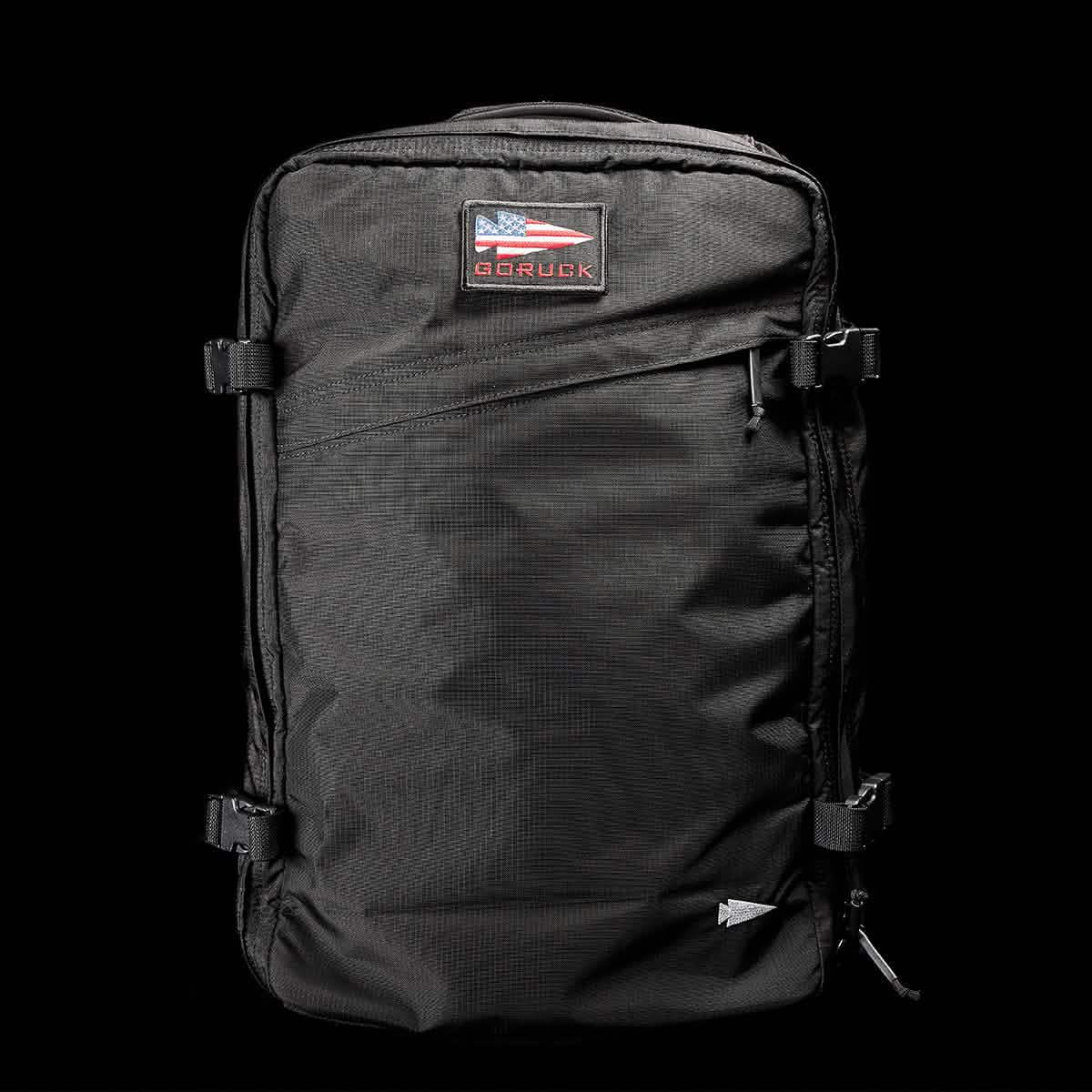 A black GORUCK GR3 - Ripstop ROBIC® backpack, crafted from durable Robic nylon, is showcased against a dark background. This carry-on rucksack features adjustable straps, multiple zippers, and a patch with a stylized American flag.