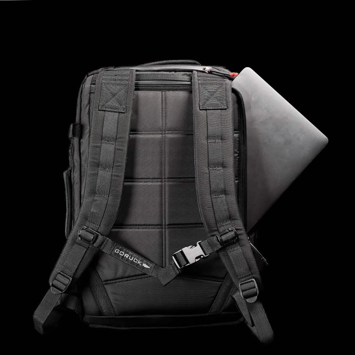 A GORUCK GR3 - Ripstop ROBIC® carry-on rucksack set against a black background, showcasing padded straps and a partially visible laptop in the main compartment. Made from durable Ripstop ROBIC® nylon, this backpack features a small logo and boasts a rugged design.