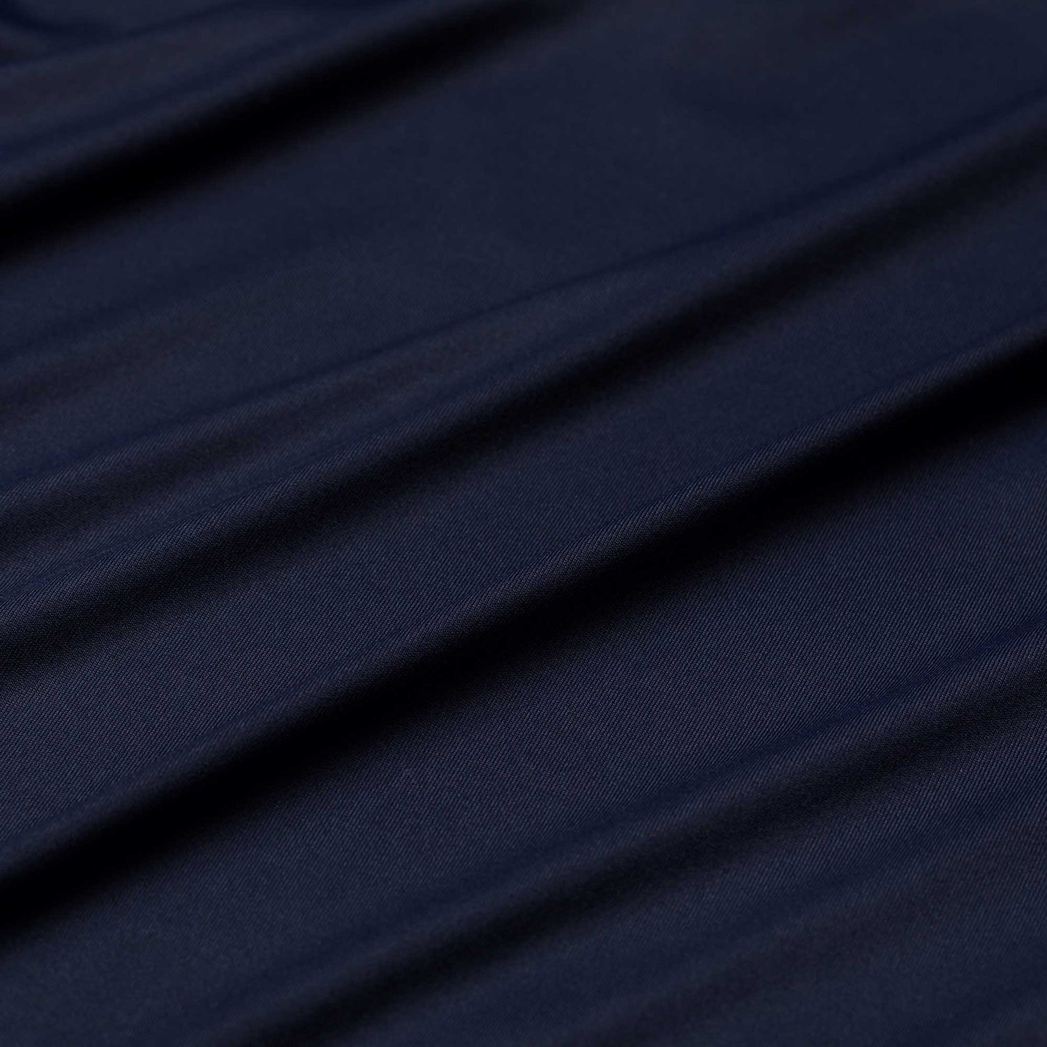 Close-up of dark blue, slightly wrinkled fabric from the Men's Long Sleeve Rucking Polo, highlighted by soft diagonal folds—crafted in Merino wool for moisture-wicking and odor resistance.