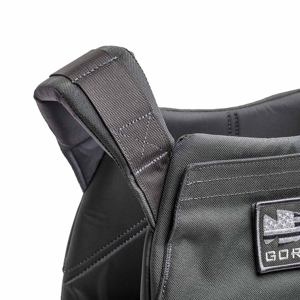 Close-up of the Rucking Weight Vest's black shoulder strap, showcasing detailed stitching and a front patch—perfect for rucking with Curved Ruck Plates.