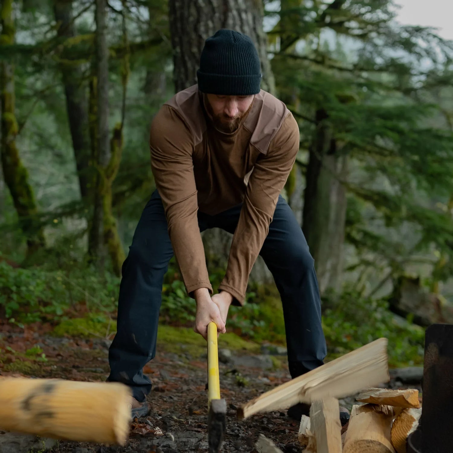 Man splitting firewood outdoors in rugged GORUCK apparel in a forest setting