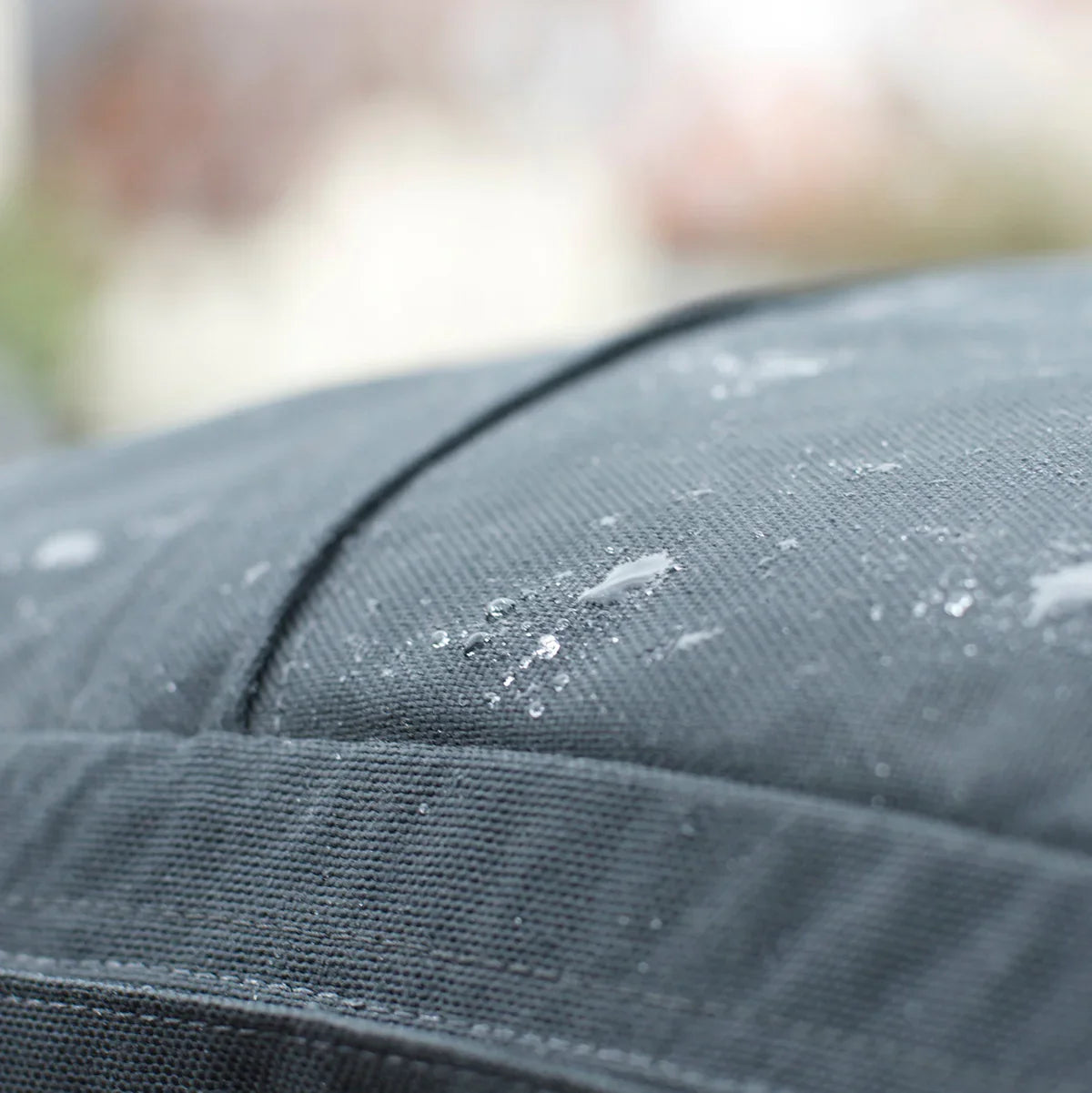 Close-up of water droplets on dark grey fabric, highlighting the GR1 USA Slick - Ballistic Nylon Cordura backpack’s Special Forces-grade quality and outdoor durability.