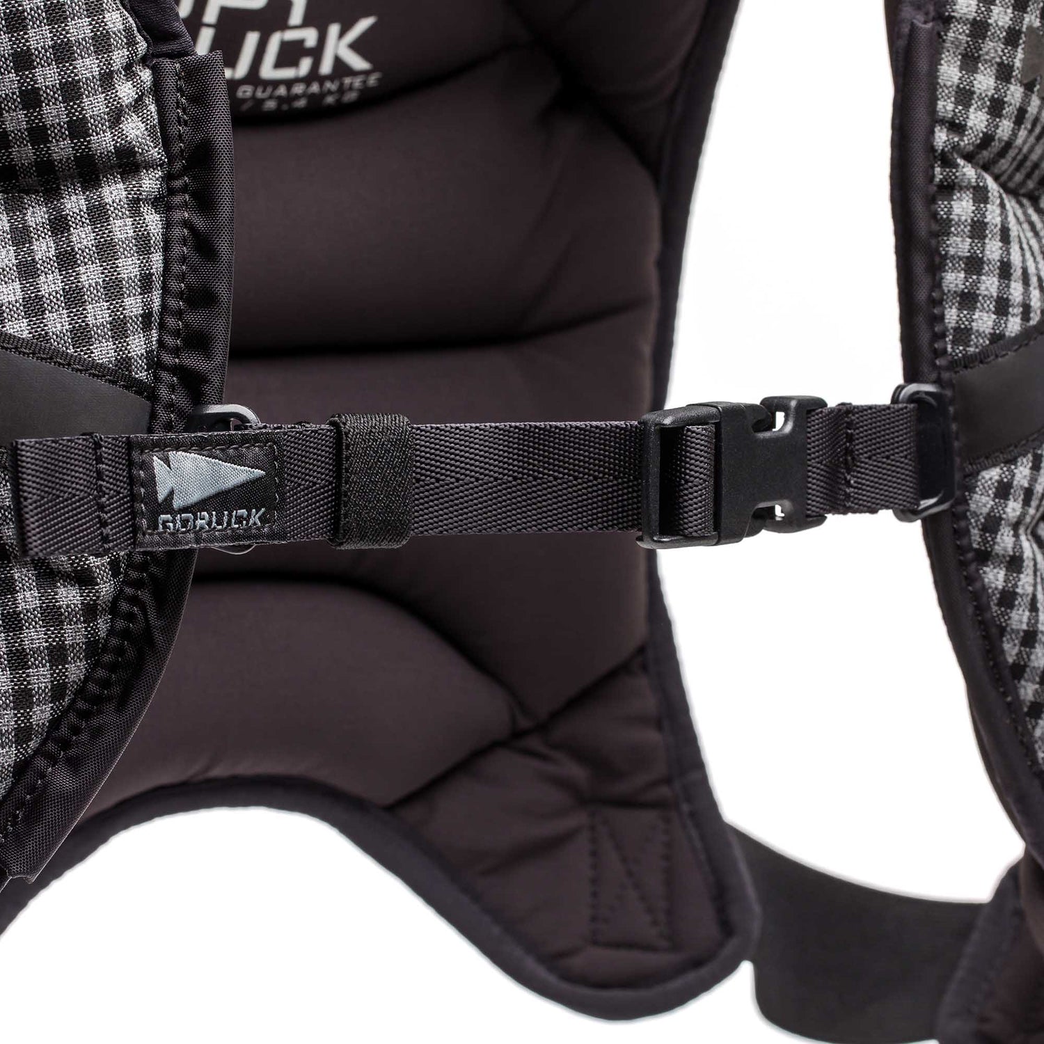 Close-up of a padded backpack strap with a black GORUCK logo tag and clipped chest buckle—built for durability, just like the Spy Ruck | Women's Weighted Vest.