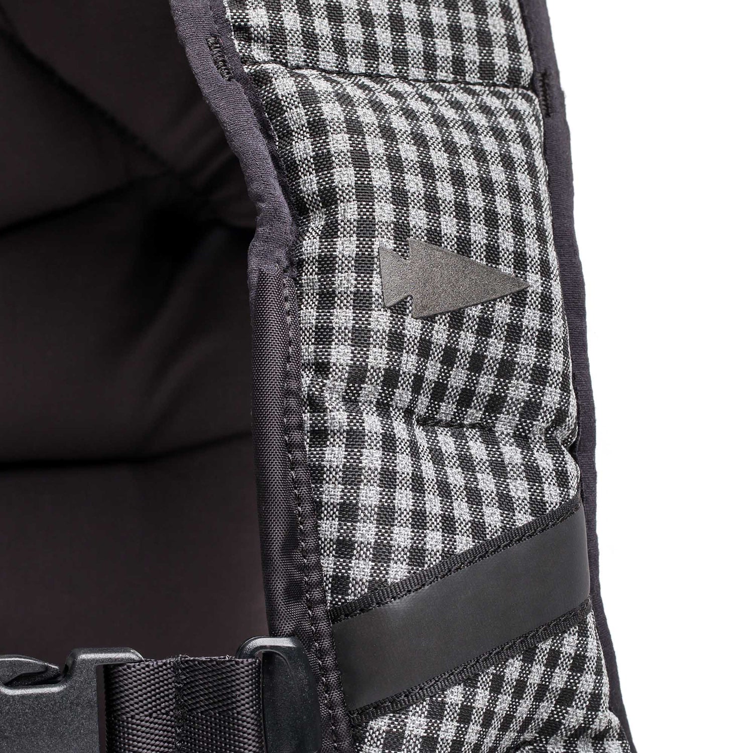 Close-up of the Spy Ruck | Women's Weighted Vest: a black and white checkered padded vest with a small arrow logo, black strap, and buckle—ideal for women seeking stylish strength training gear.