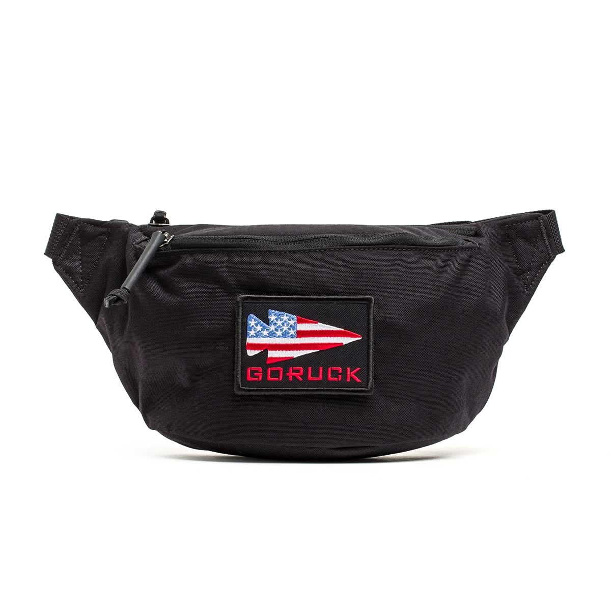 The Tactical FP1 is a black waist bag with stealth zipper pulls, an American flag patch, and red