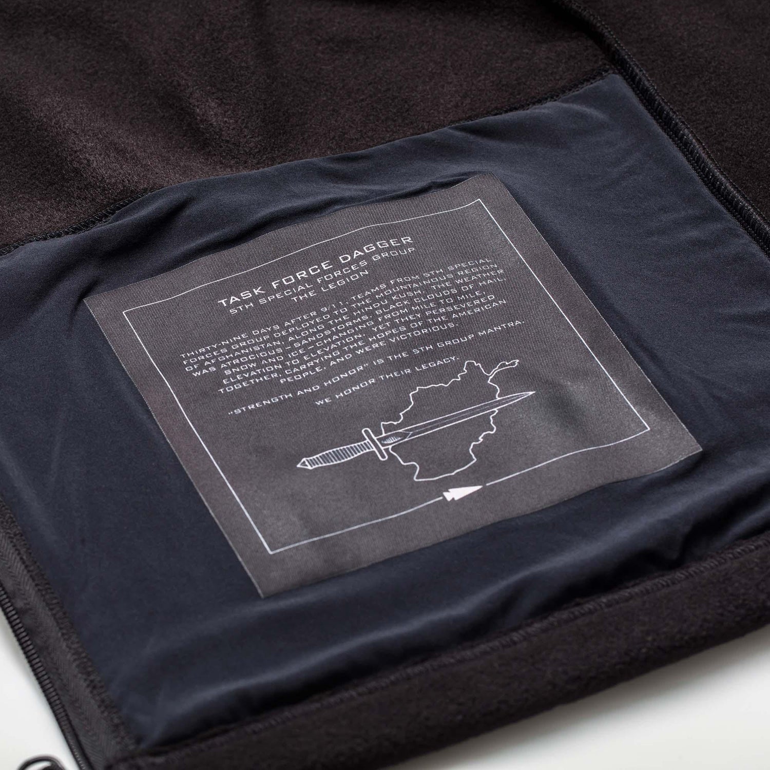 Inside view of black Task Force Dagger fleece jacket with detailed print honoring 5th Special Forces Group and a dagger and map graphic