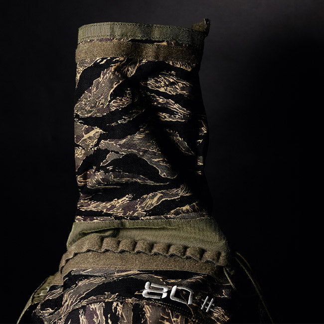 A close-up of a camouflage-patterned jacket with a high collar against a black background.