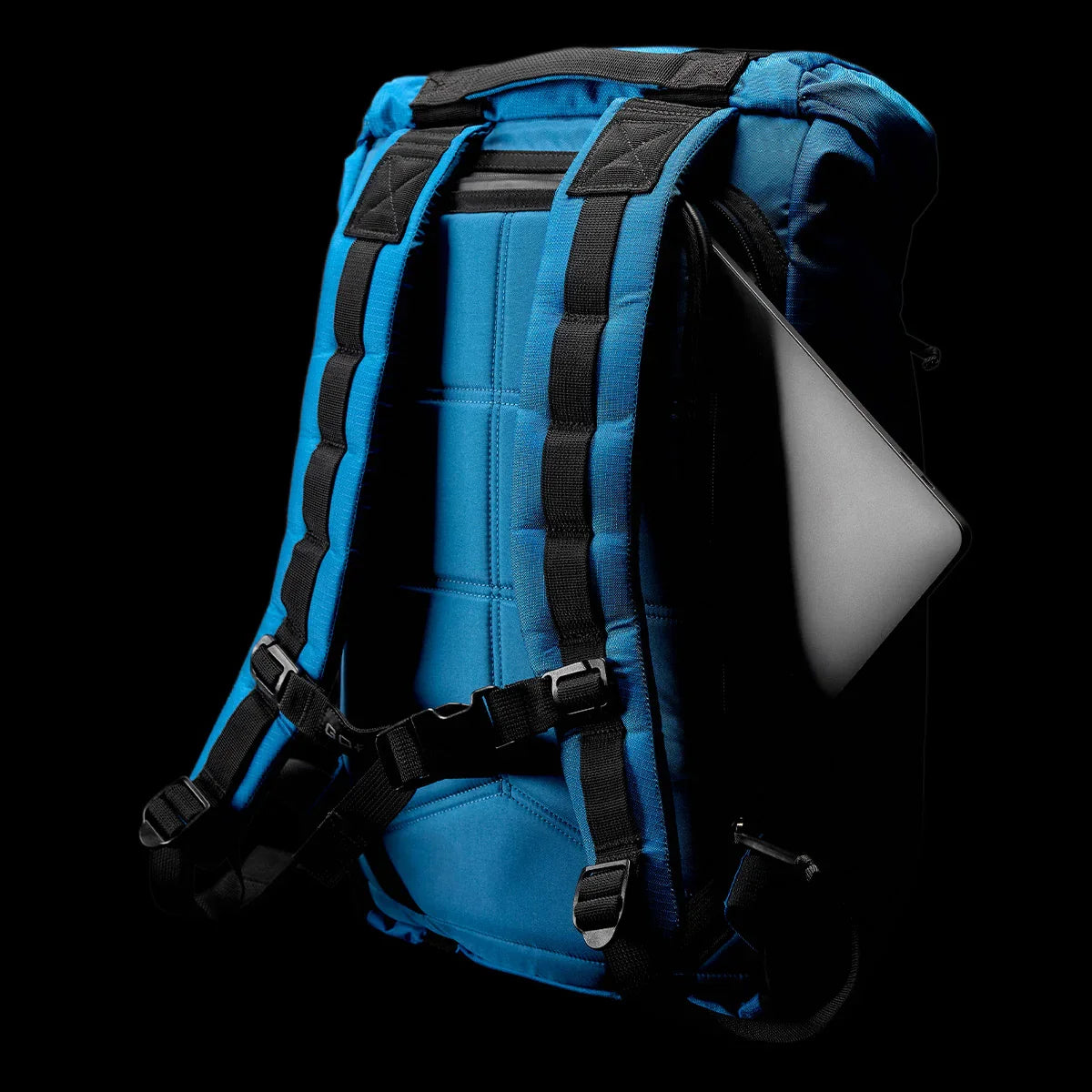 GORUCK blue rucksack with black straps and a laptop in the back compartment, on black background