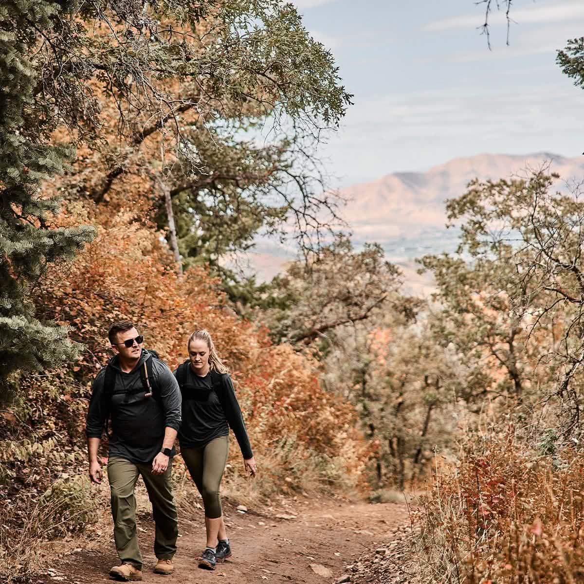 Two people rucking in GORUCK gear on a scenic autumn trail surrounded by colorful trees