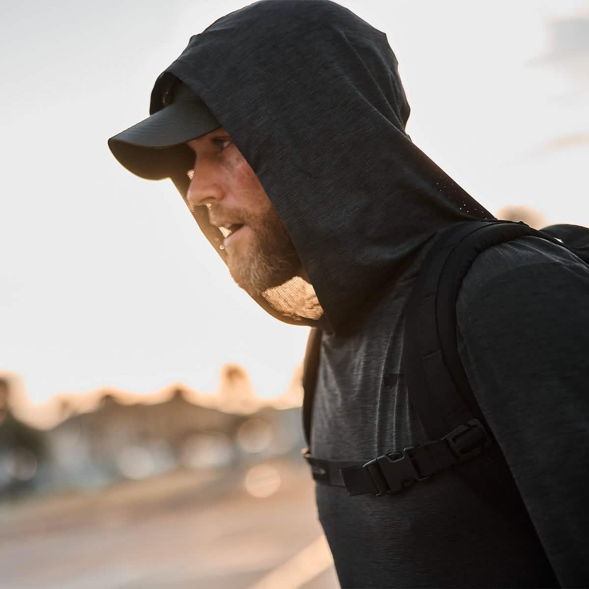 Man rucking outdoors wearing GORUCK ToughMesh charcoal hoodie and black backpack at sunset