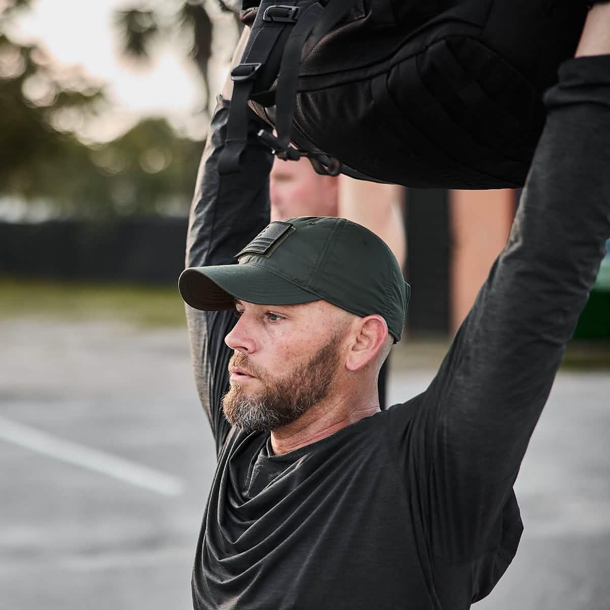 Man in charcoal GORUCK Tough Mesh Hoodie lifting rucksack outdoors during workout