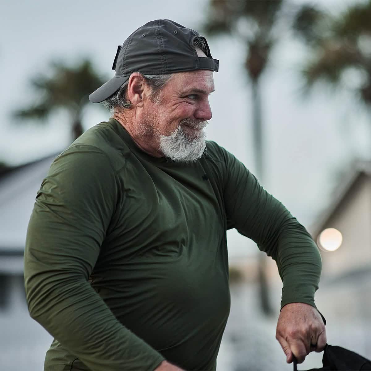 Man in green GORUCK ToughMesh long sleeve shirt outdoors, wearing a backwards cap