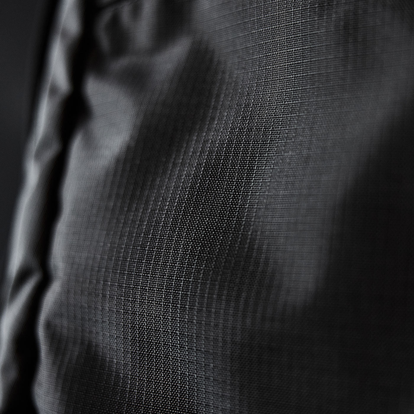Close-up of dark grey textured fabric with a subtle grid pattern and soft folds.