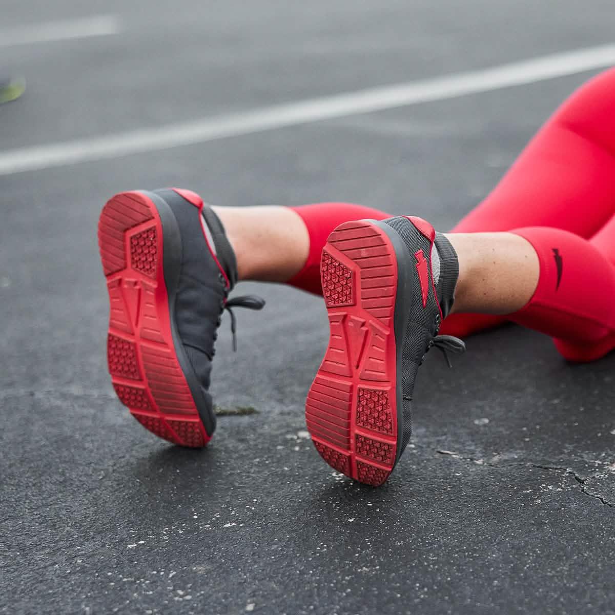 GORUCK women's ballistic trainer in wolf grey and red, worn outdoors on pavement.