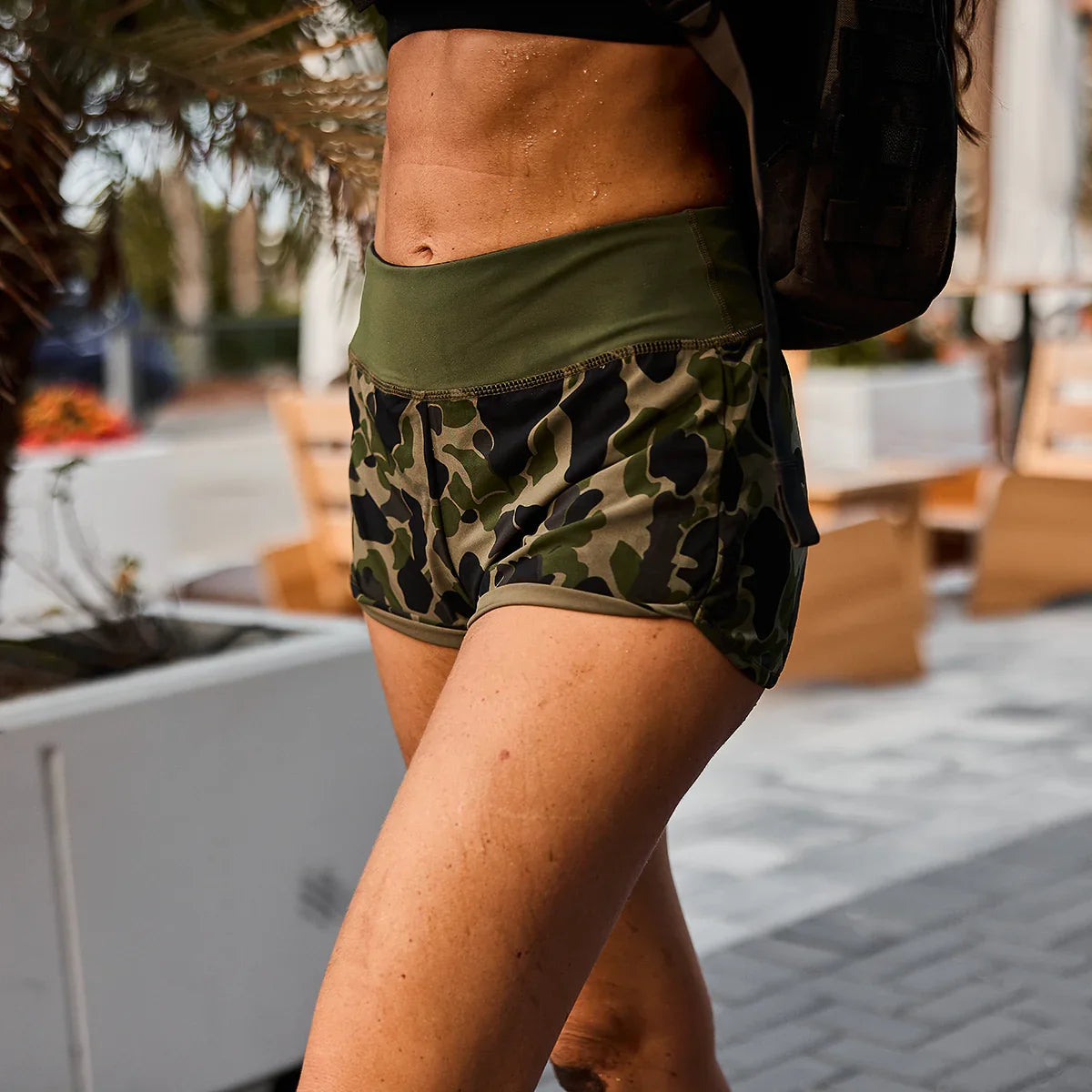 Close-up of a woman wearing green camo women's training shorts outdoors, showcasing tough and durable rucking gear