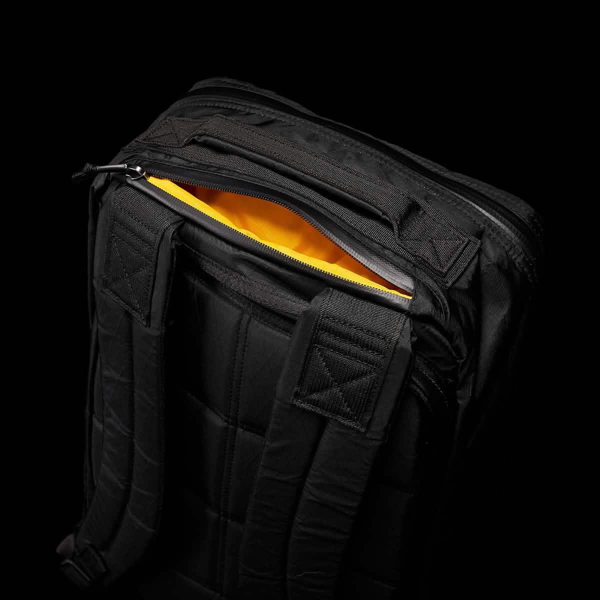 Black GORUCK rucksack with padded shoulder straps and yellow interior shown in close-up on black background