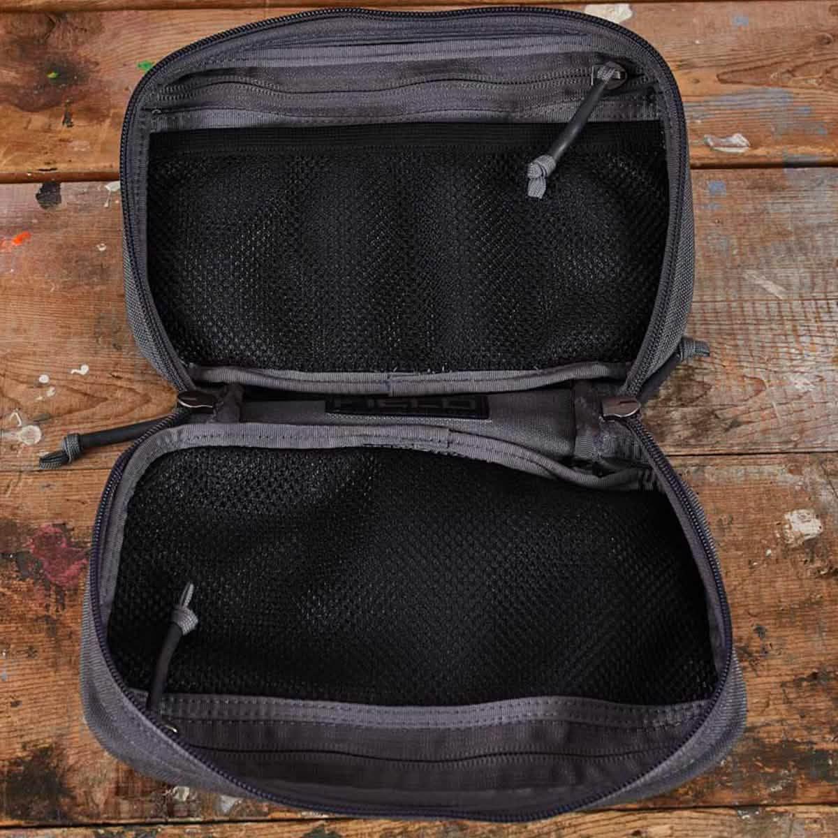 Open grey GORUCK organizer pouch with black mesh compartments on wooden surface