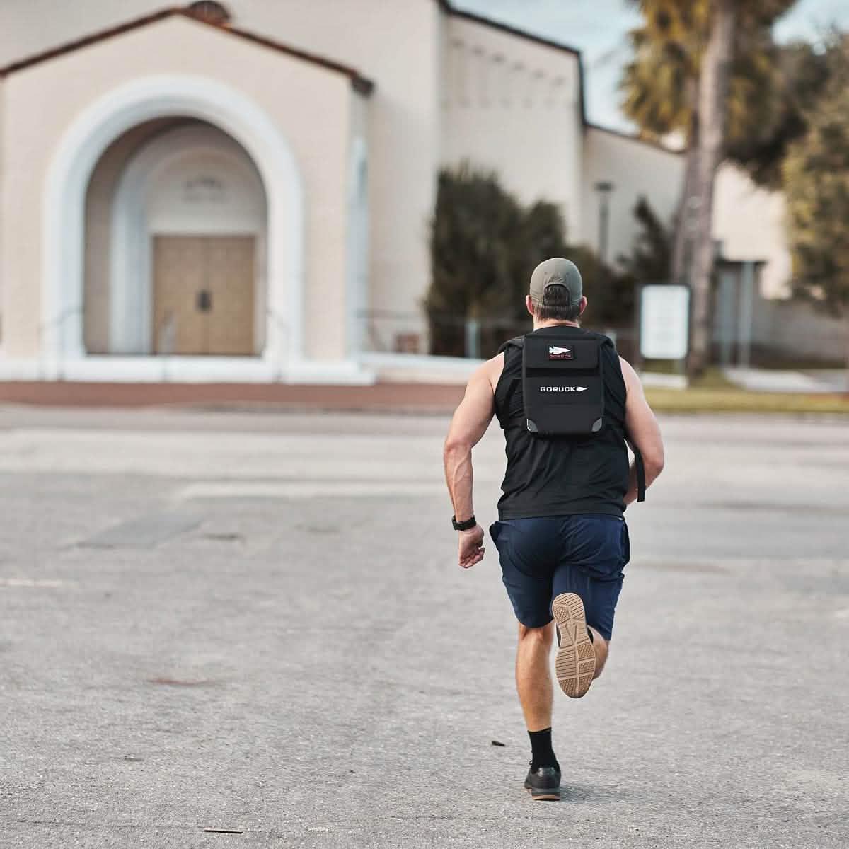 Man running outdoors wearing GORUCK ballistic trainer weighted vest and athletic gear