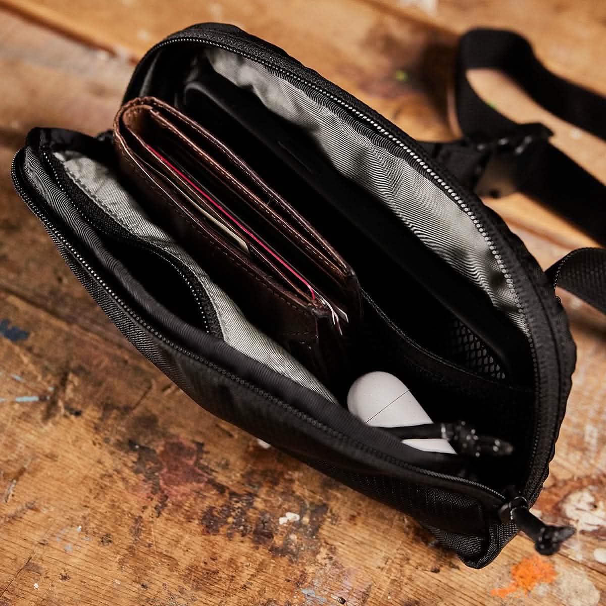 GORUCK belt bag open showing organized wallet and accessories on a wooden surface