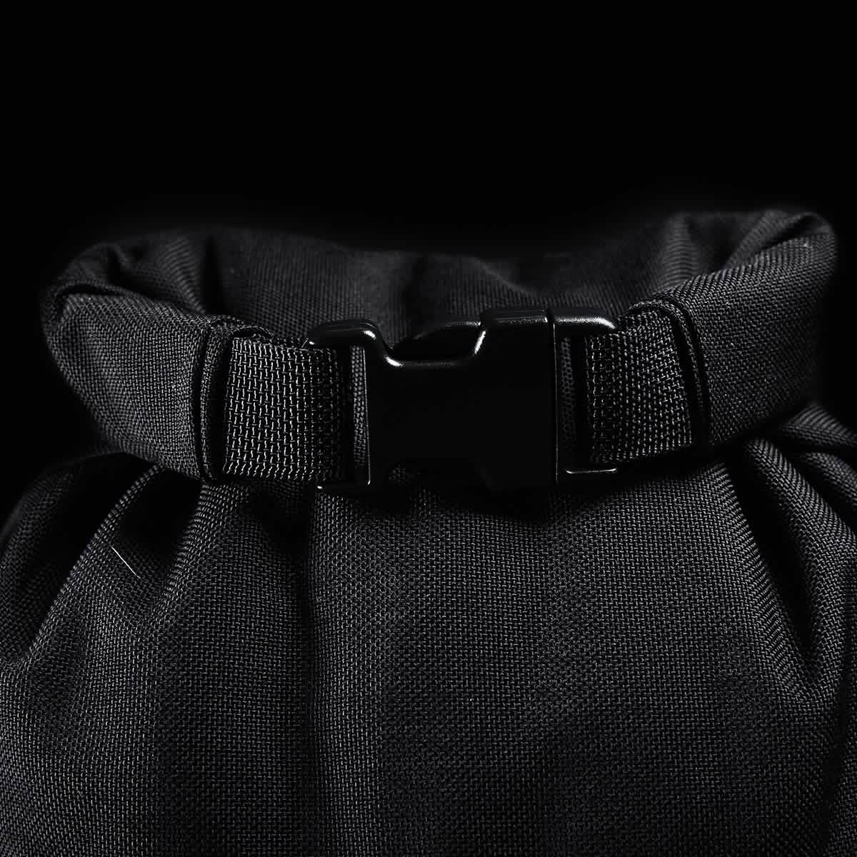 Close-up of the Brick Bag (5-50 LBS) from GORUCK, featuring a military-inspired black roll-top design with buckle closure against a dark background. The textured fabric highlights the bag's durability and versatile training applications.